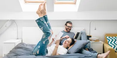  Un chico y una chica riéndose y leyendo unos libros en un dormitorio. 