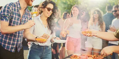 Un grupo de amigos en una fiesta barbacoa alrededor de una parrilla de barbacoa